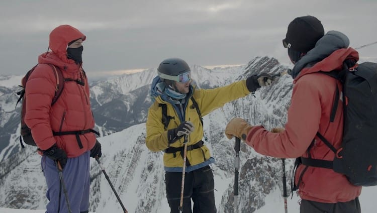 three backcountry skiers talking on top mountain