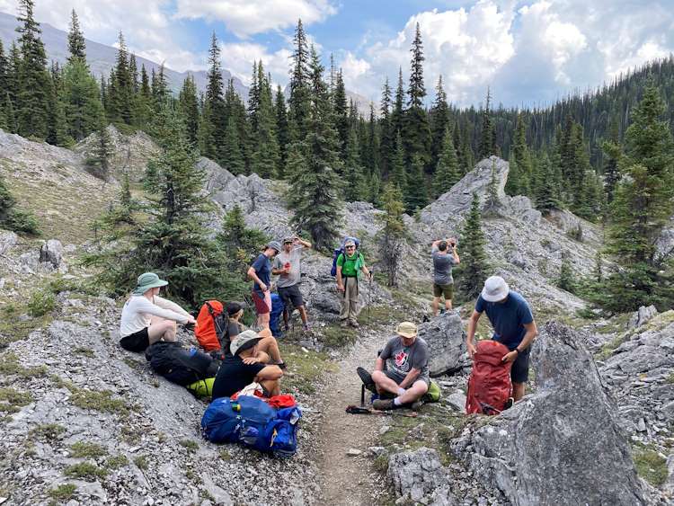 9 hikers resting on rocks in mountains in the summer season