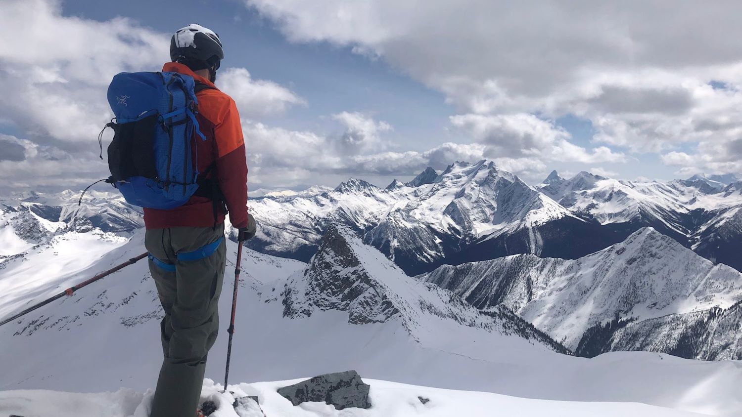 Back of backcountry skier looking over snowy mountain peak