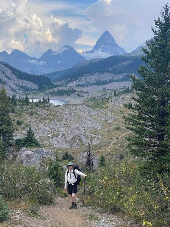 lone hiker posing at a mountainous backdrop with a pond in the summer