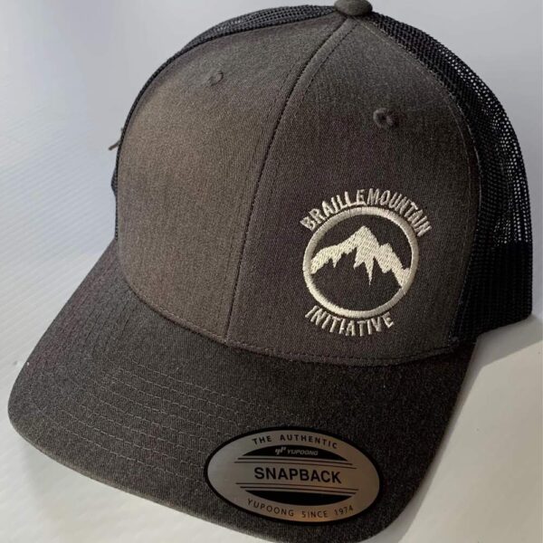 Front view of snapback trucker hat, dark grey color, with Braille Mountain Initiative logo stitched