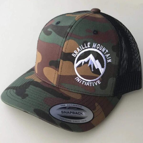 Front view of snapback trucker hat, camouflaged color, with Braille Mountain Initiative logo stitched