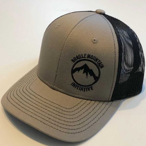 Front view of snapback trucker hat, light grey color, with Braille Mountain Initiative logo stitched