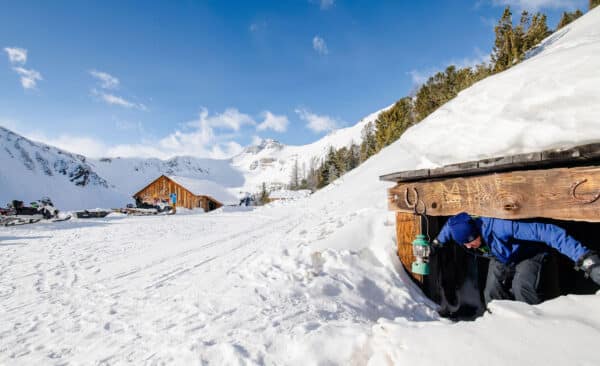 mountain winter scene with cabin in the background and low height shed in the foreground.