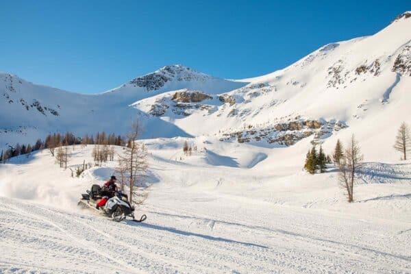 Clear blue winter skies with snowy mountain and snowmobile on the flat section