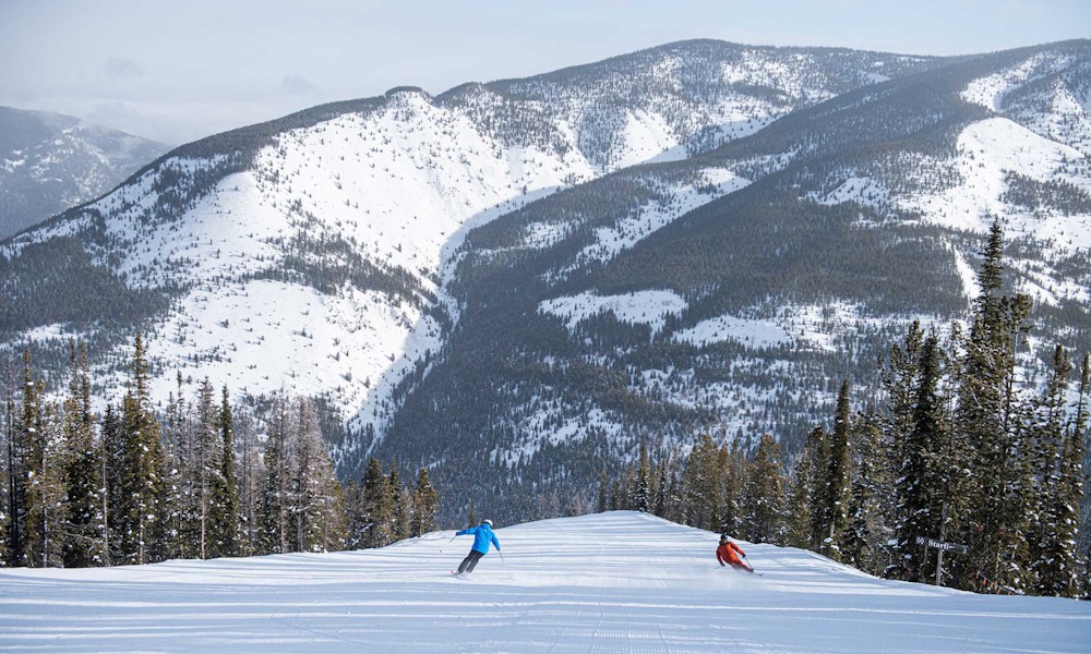 Big wide winter mountain resort trail with Skier and Snowboarder