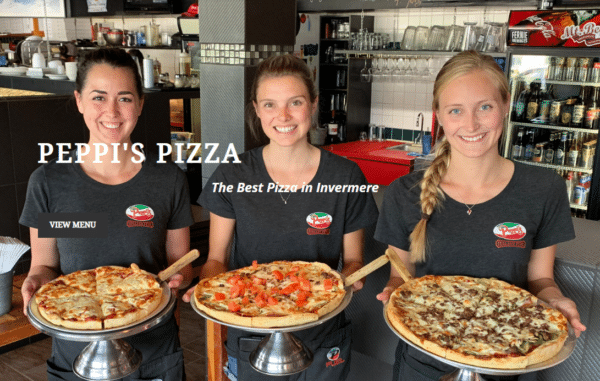 Three women dressed in black t-shirts with the Peppi's pizzeria logo on the left breast hold a large pizza in front of them.