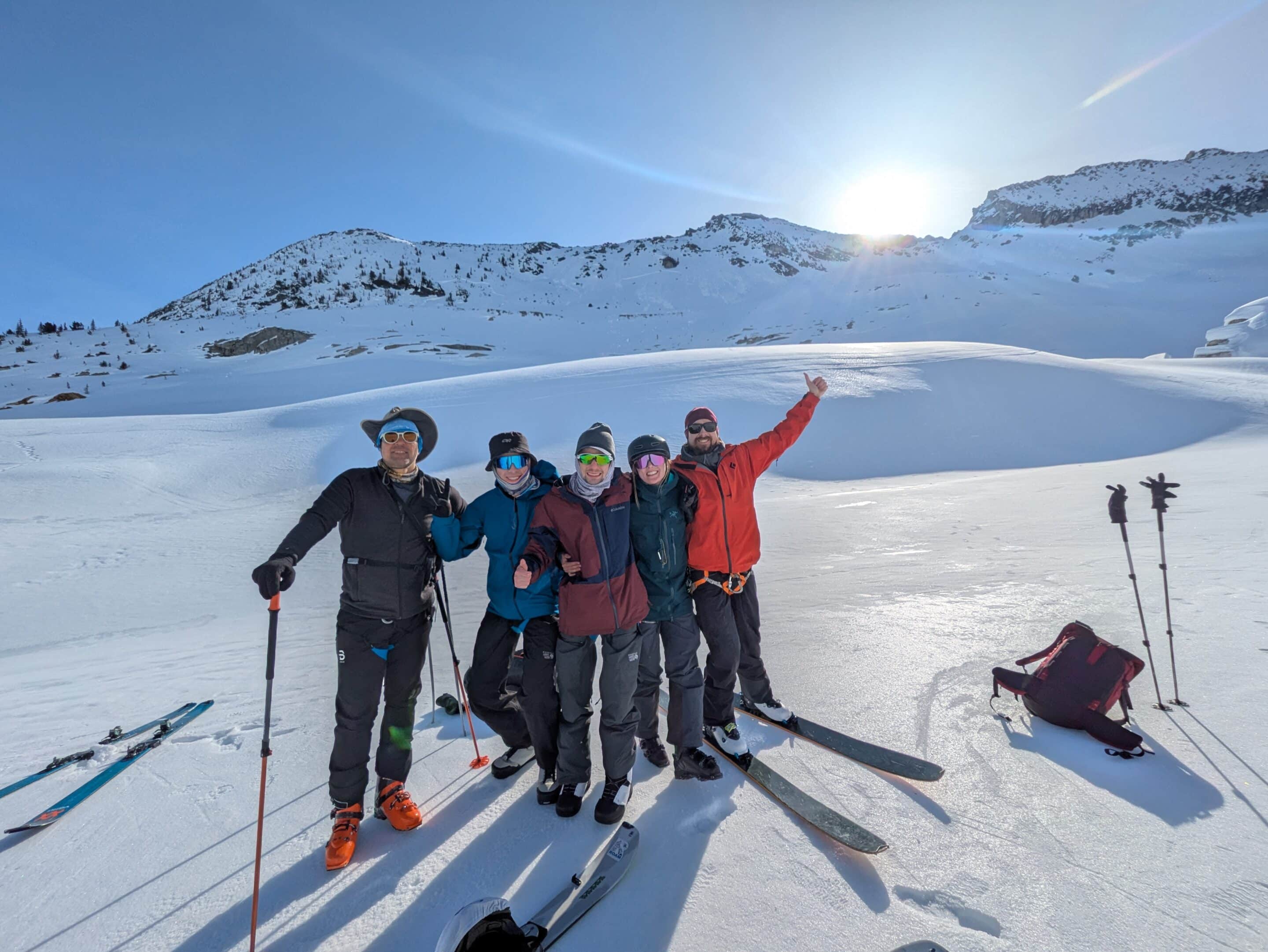 Mark Bentz, Quinn Ceplis, Lucas Desrocher, Alex Elkerton, and Tyson Rettie pose for a photo during a break while travelling up Nordic Glacier, as the sun is just peaking over the ridgeline in the background.