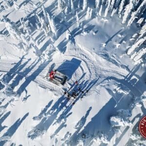 Overhead scenery of snowy forest area with Cat Skiing Vehicle and skiers