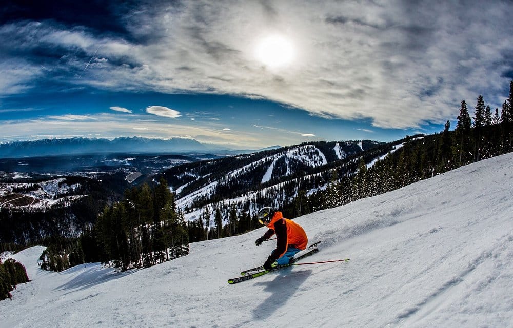A skier descends down a groomed run on a bluebird day.