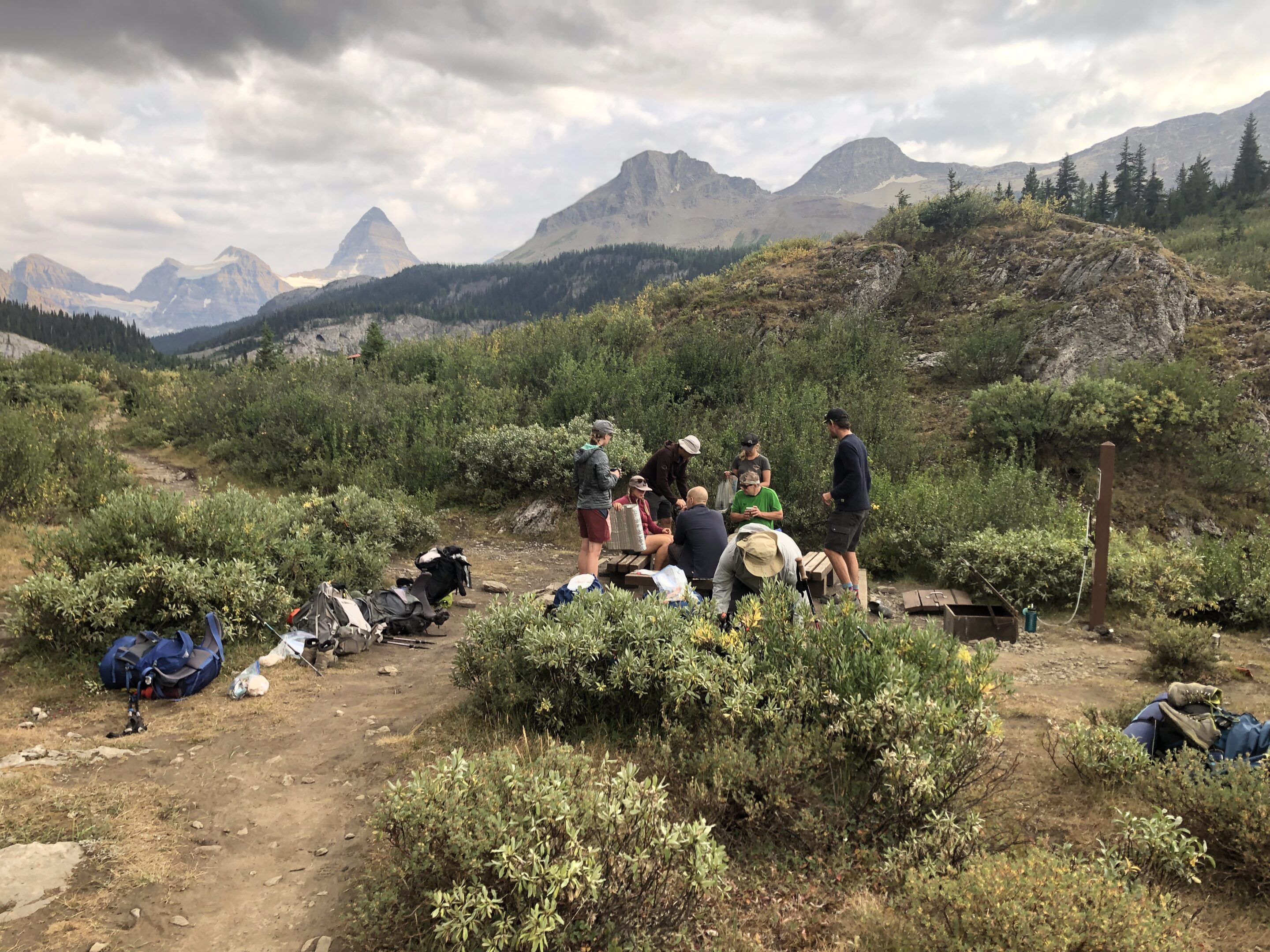 A group of participants and volunteers skinning up a open glaciated slope between two massive rock walls.